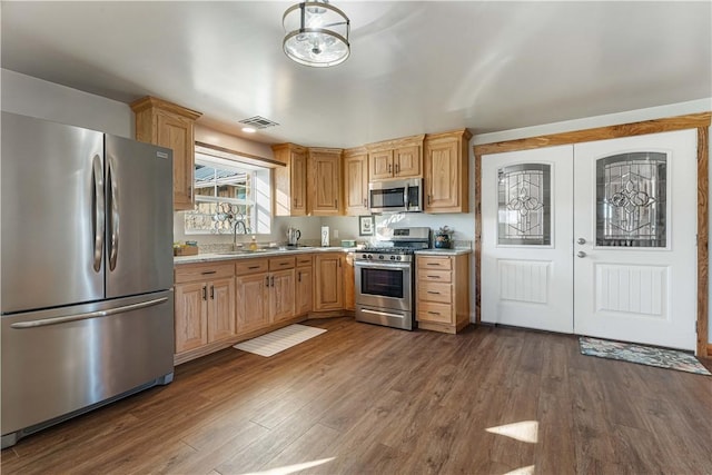 kitchen featuring appliances with stainless steel finishes, sink, light stone counters, and dark hardwood / wood-style floors