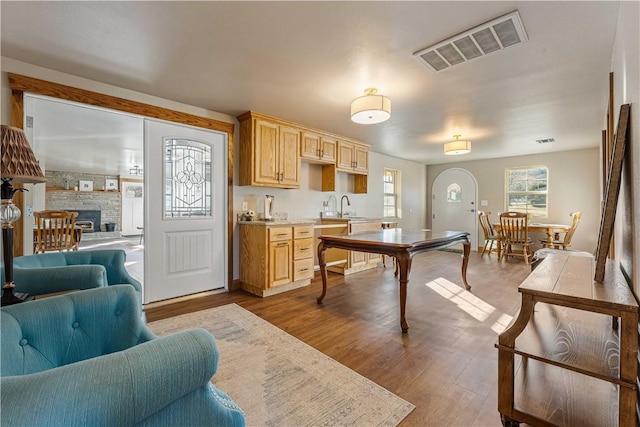 kitchen with a fireplace, light hardwood / wood-style floors, light brown cabinets, and sink