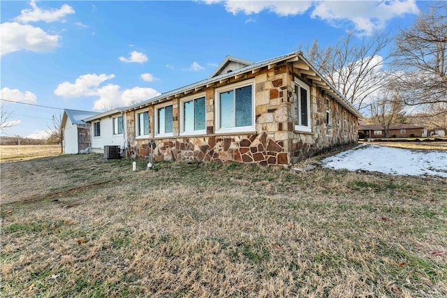 view of side of property with central AC unit and a yard