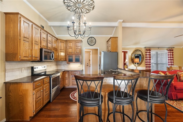 kitchen featuring dark wood-type flooring, appliances with stainless steel finishes, kitchen peninsula, a notable chandelier, and decorative backsplash