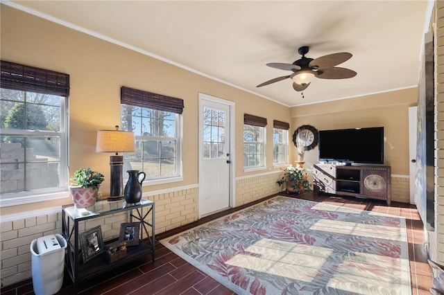 interior space with ceiling fan, ornamental molding, and brick wall