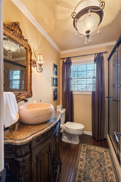 bathroom with crown molding, hardwood / wood-style flooring, vanity, an enclosed shower, and toilet