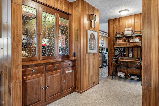 bar featuring light colored carpet, range with electric cooktop, a textured ceiling, and wood walls