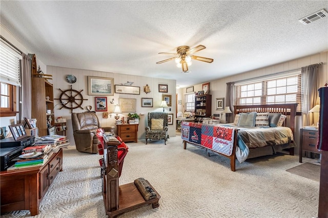 bedroom featuring a textured ceiling, light colored carpet, and ceiling fan