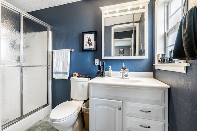 bathroom featuring walk in shower, vanity, toilet, and a textured ceiling