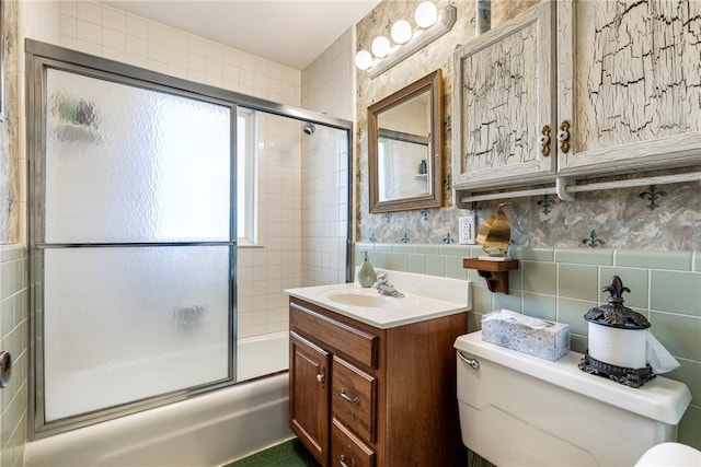 full bathroom with combined bath / shower with glass door, tile walls, decorative backsplash, vanity, and toilet