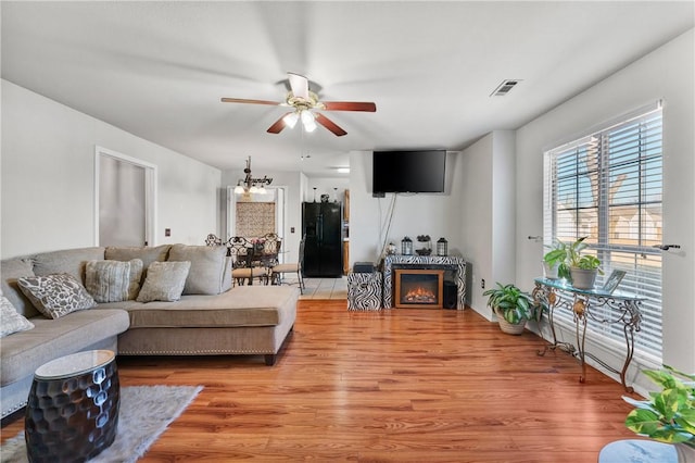 living room with ceiling fan with notable chandelier and light wood-type flooring