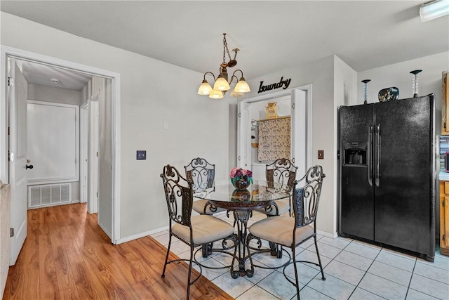 dining space featuring light wood-type flooring and a notable chandelier