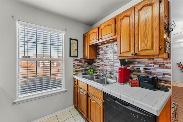 kitchen featuring tasteful backsplash, dishwasher, tile countertops, sink, and light tile patterned floors