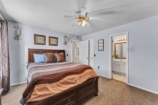 bedroom featuring ceiling fan, light colored carpet, and connected bathroom