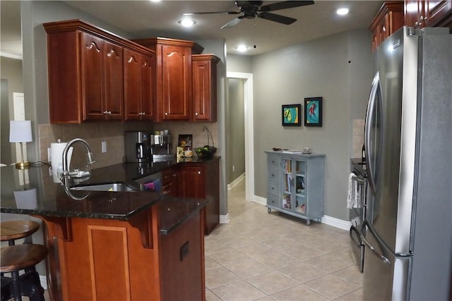 kitchen with stainless steel refrigerator, tasteful backsplash, sink, a kitchen breakfast bar, and kitchen peninsula