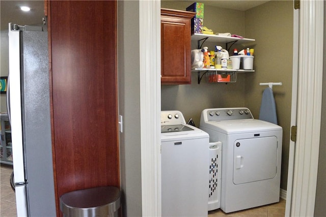 clothes washing area with light tile patterned floors, cabinets, and washing machine and clothes dryer