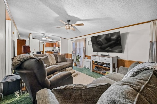 carpeted living room with a textured ceiling, crown molding, and wooden walls