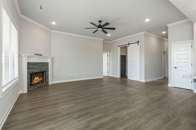 unfurnished living room featuring ceiling fan, dark hardwood / wood-style flooring, a barn door, and plenty of natural light