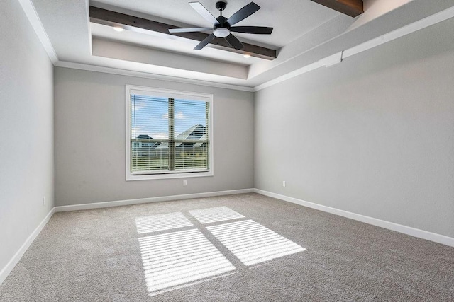 empty room with a raised ceiling, light colored carpet, ceiling fan, and crown molding