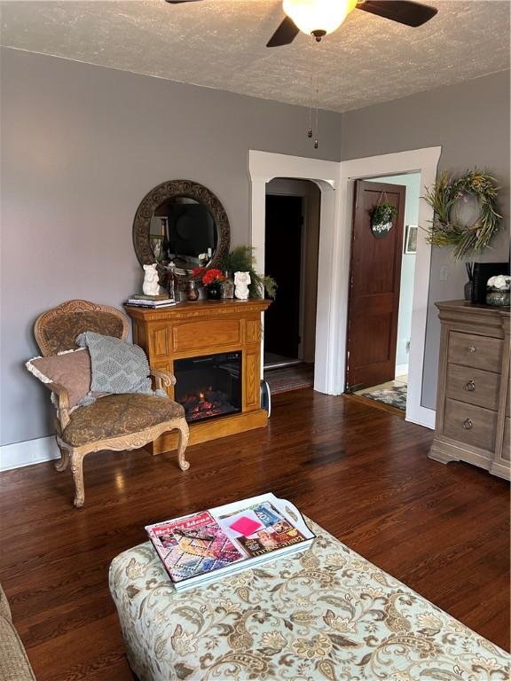 sitting room with ceiling fan, dark wood-type flooring, and a textured ceiling