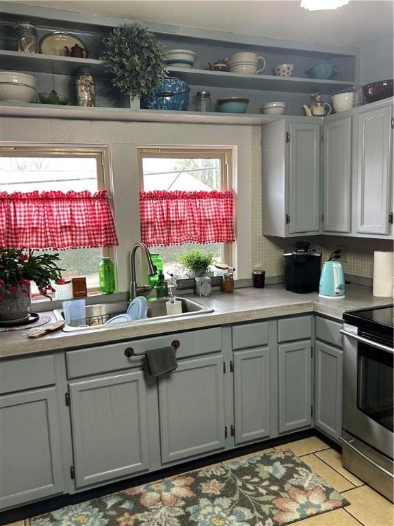 kitchen featuring light tile patterned floors, electric range, sink, and gray cabinets