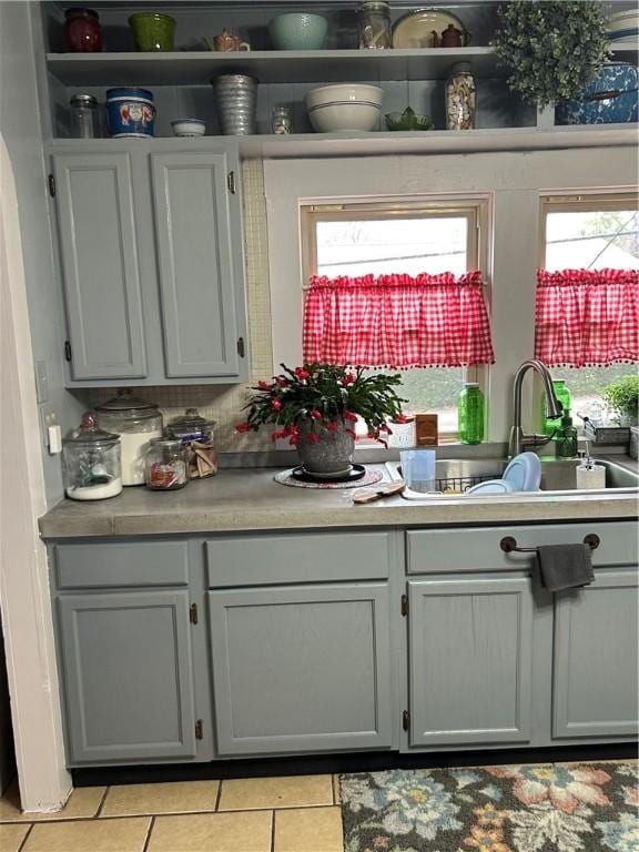 kitchen with gray cabinets, light tile patterned flooring, and sink