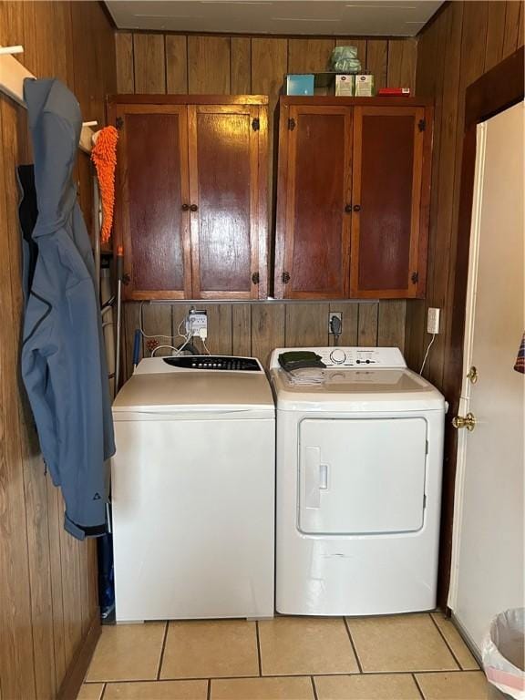 washroom featuring cabinets, separate washer and dryer, light tile patterned flooring, and wooden walls