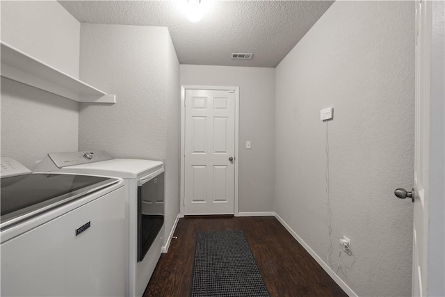 laundry area featuring dark hardwood / wood-style floors, washing machine and dryer, and a textured ceiling