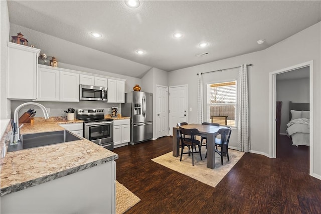 kitchen with dark wood-type flooring, stainless steel appliances, sink, and white cabinets