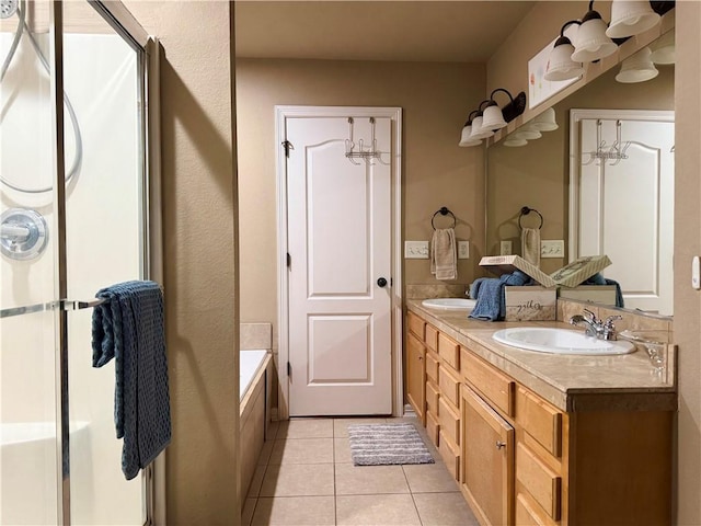 bathroom with a relaxing tiled tub, tile patterned floors, and vanity