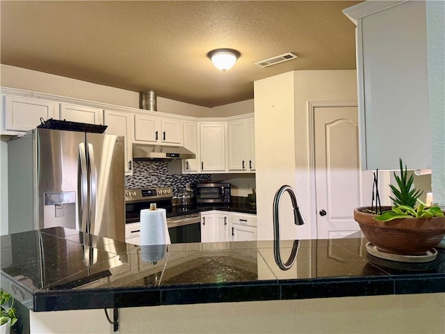 kitchen featuring a kitchen bar, kitchen peninsula, white cabinetry, appliances with stainless steel finishes, and a textured ceiling