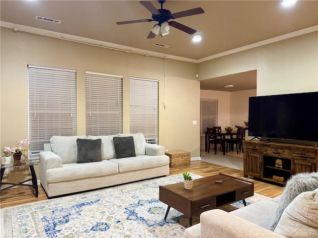 living room with ceiling fan, light wood-type flooring, and crown molding