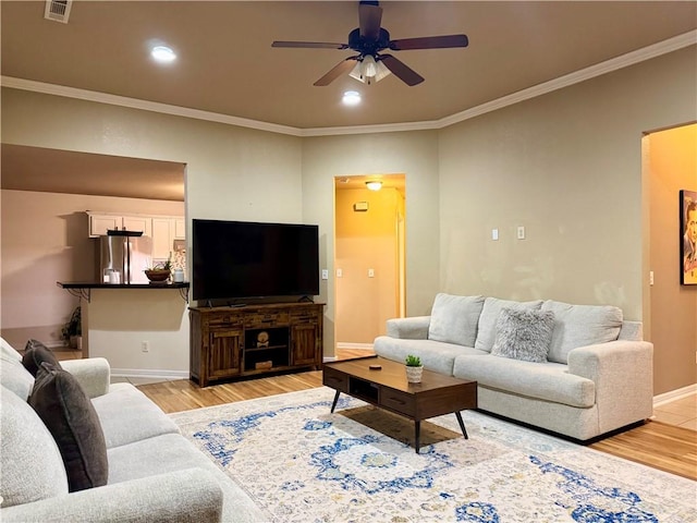 living room featuring ceiling fan, crown molding, and light wood-type flooring