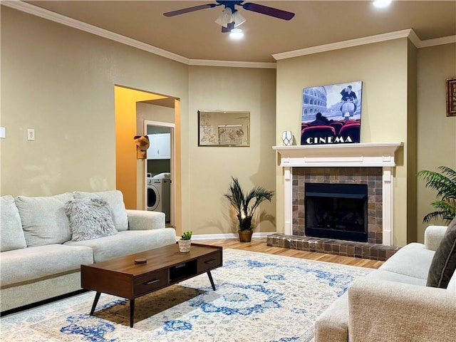 living room with hardwood / wood-style flooring, ornamental molding, ceiling fan, and a fireplace