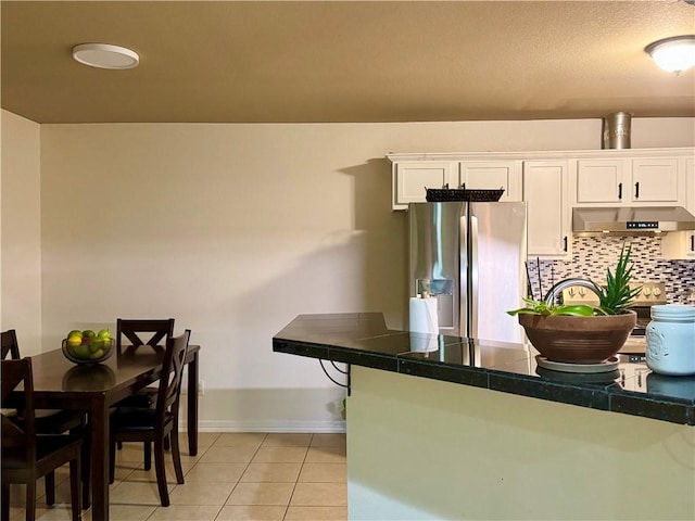 kitchen with tile counters, white cabinets, stainless steel fridge, and light tile patterned flooring