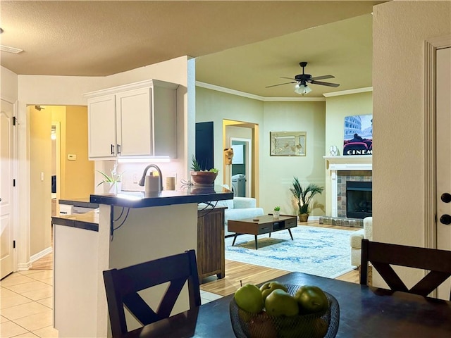 kitchen with light tile patterned floors, kitchen peninsula, a breakfast bar area, ornamental molding, and white cabinets