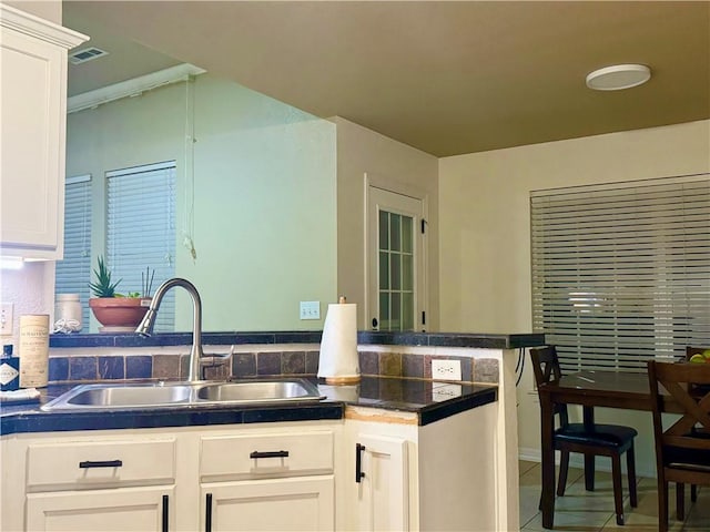 kitchen with sink, white cabinetry, kitchen peninsula, and tile patterned flooring