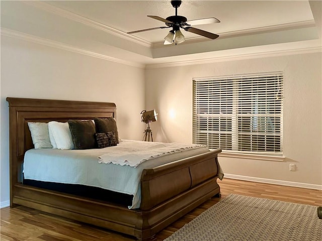 bedroom featuring ceiling fan, a raised ceiling, ornamental molding, and hardwood / wood-style flooring