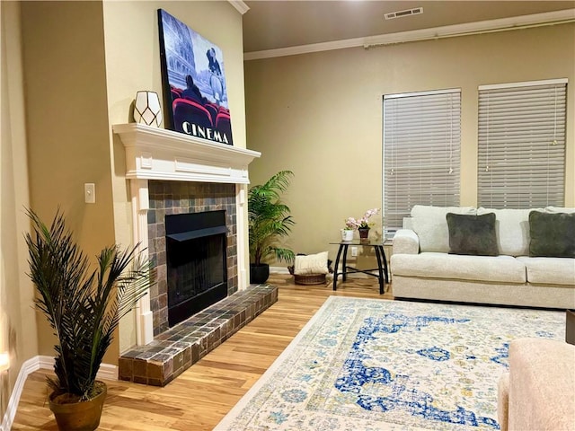 living room featuring hardwood / wood-style floors, crown molding, and a fireplace