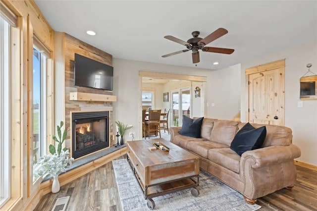 living room with ceiling fan, a fireplace, and hardwood / wood-style flooring