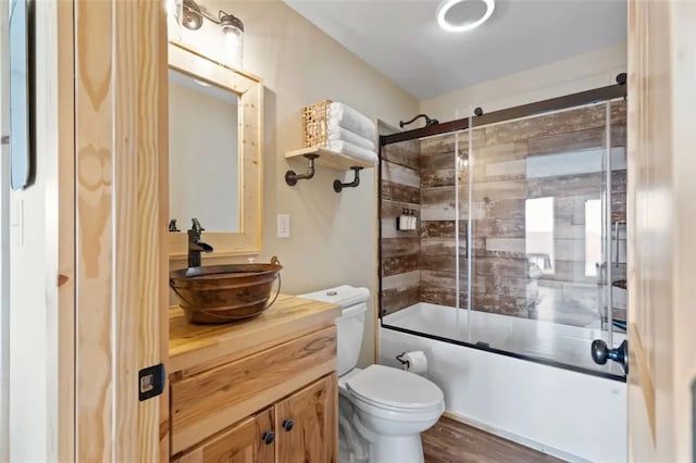 full bathroom featuring combined bath / shower with glass door, vanity, toilet, and hardwood / wood-style floors