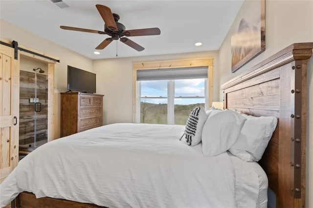 bedroom with ceiling fan and a barn door