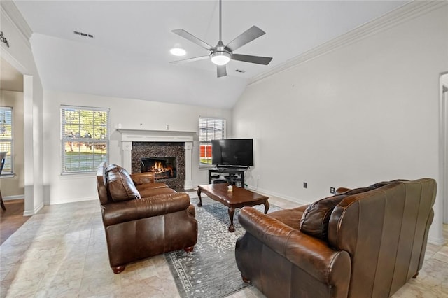 living room featuring vaulted ceiling, a premium fireplace, crown molding, and ceiling fan