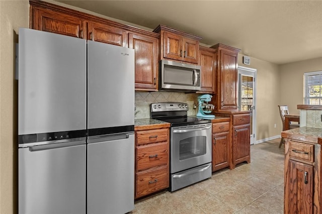 kitchen with decorative backsplash, stainless steel appliances, and light tile patterned flooring