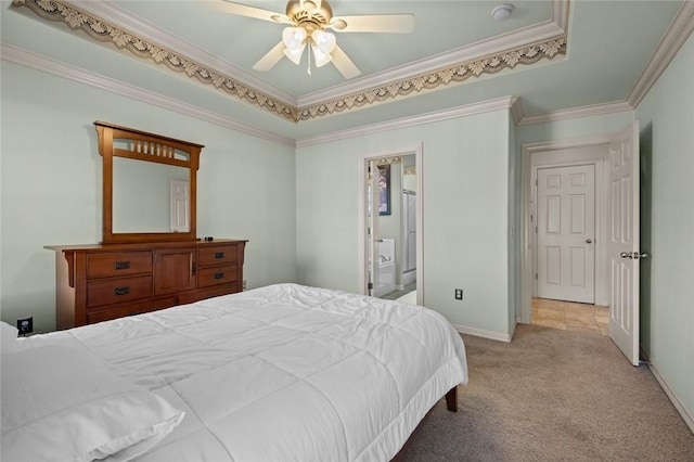 bedroom featuring ensuite bathroom, ceiling fan, a raised ceiling, light colored carpet, and crown molding