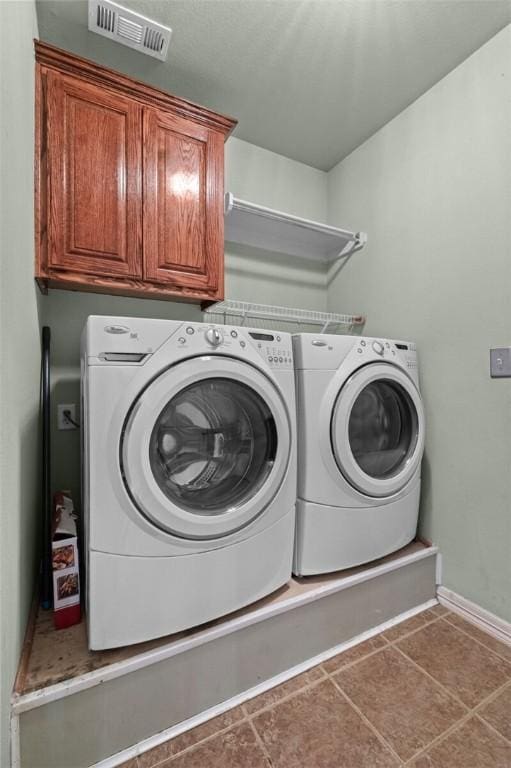 laundry room featuring washer and dryer, cabinets, and tile patterned floors