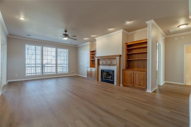 unfurnished living room with ceiling fan, hardwood / wood-style floors, crown molding, and a tiled fireplace