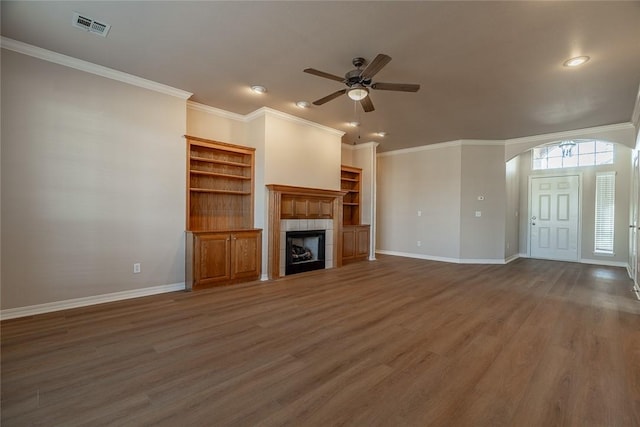 unfurnished living room with ceiling fan, dark hardwood / wood-style floors, ornamental molding, and a fireplace