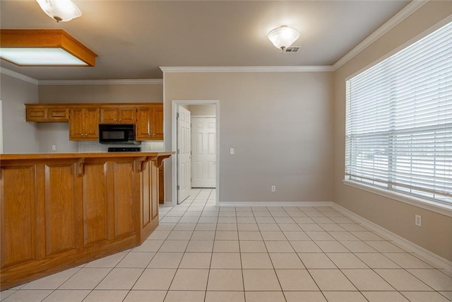 kitchen with a kitchen bar, light tile patterned flooring, and ornamental molding