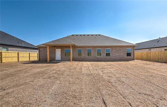 rear view of property featuring brick siding and a fenced backyard