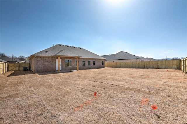 rear view of house featuring a fenced backyard and brick siding