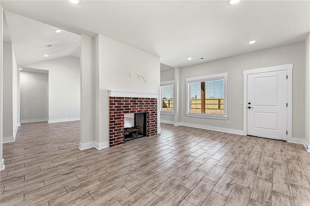 unfurnished living room with recessed lighting, light wood-style floors, a fireplace, and vaulted ceiling