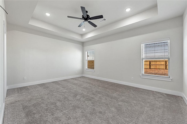 empty room featuring visible vents, recessed lighting, a raised ceiling, and baseboards