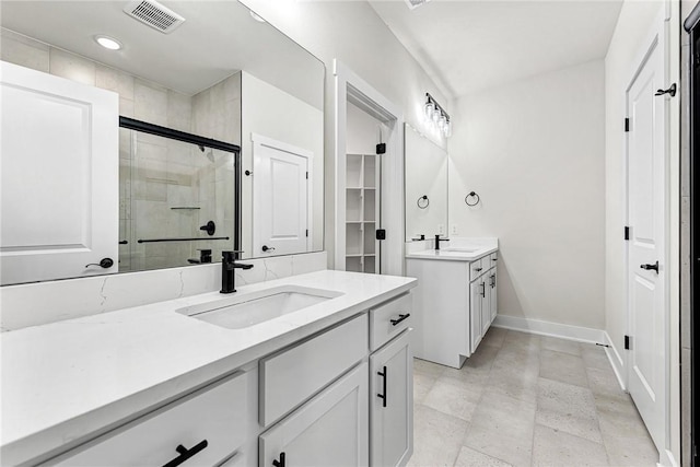 bathroom with a shower stall, two vanities, visible vents, and a sink